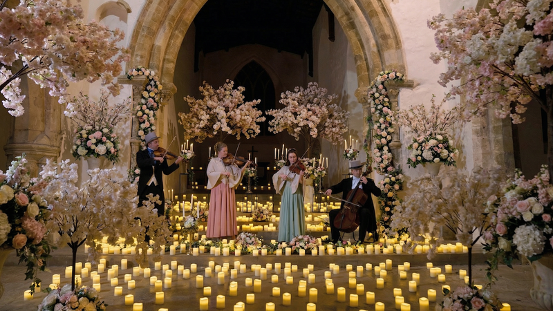 Four string musicians performing as a quartet in a floral, Regency-style environment with an elegant, classical atmosphere.