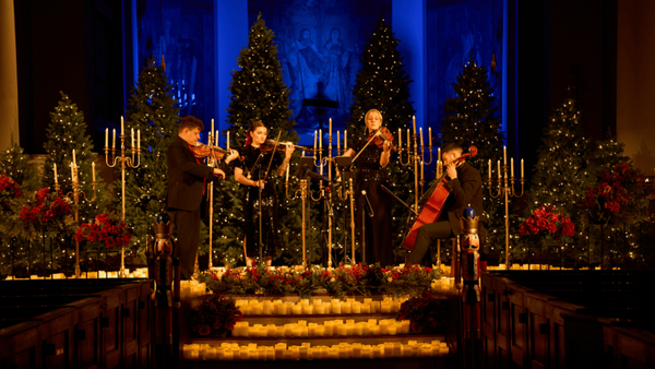 A festive holiday concert scene inside a cathedral, featuring a string quartet performing in front of decorated Christmas trees and candelabras with glowing candles.